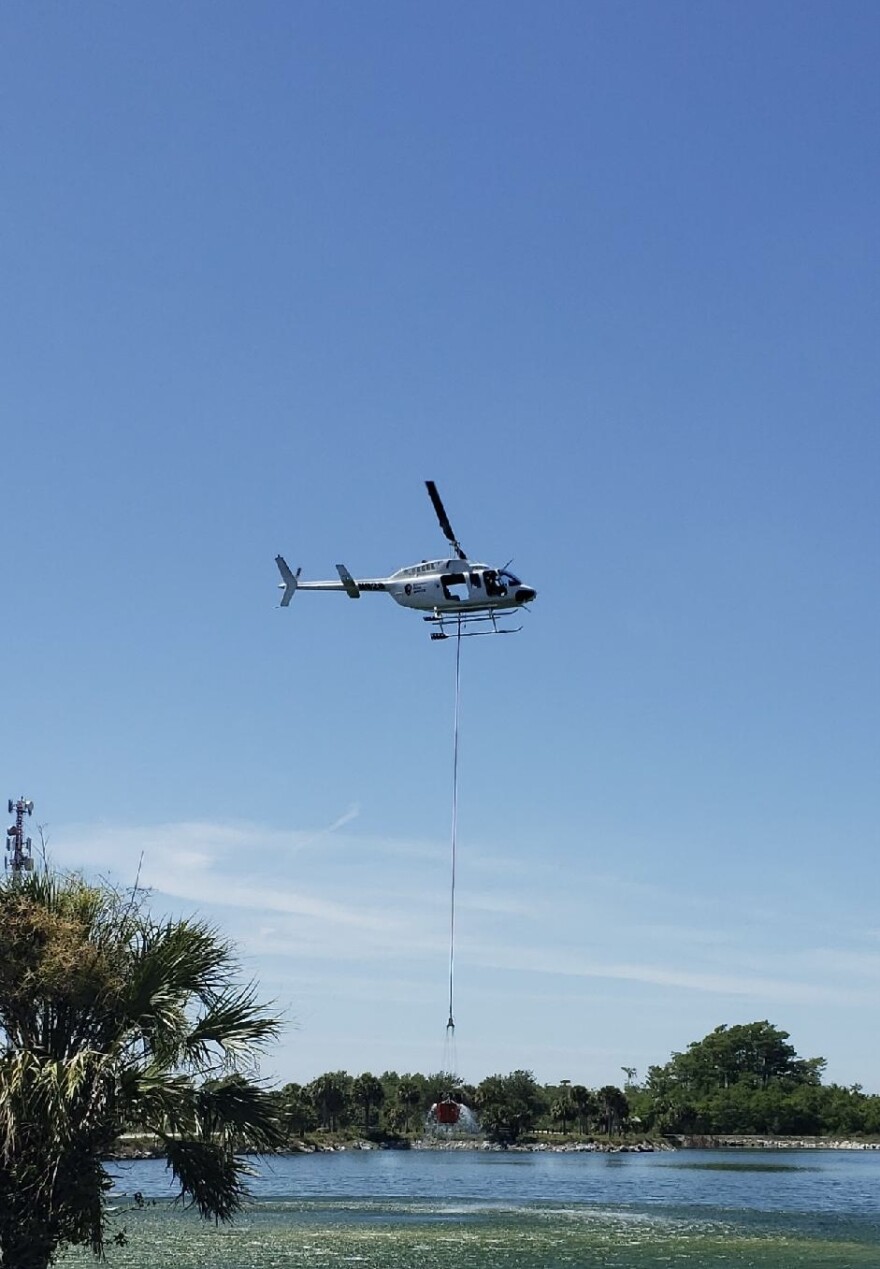 Fire crews gather water via helicopter to spread on a nearly 700-acre wildfire in the Big Cypress National Preserve Wednesday.