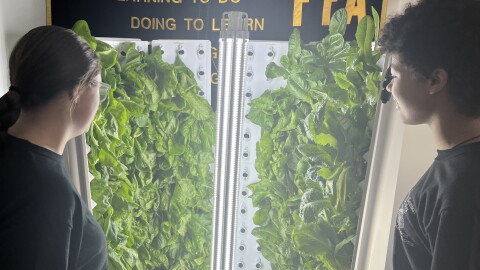 Dylan Miller and Lavender Johnson, high school students in Lima City School District, gaze at lettuce being grown on a hydroponic tower.