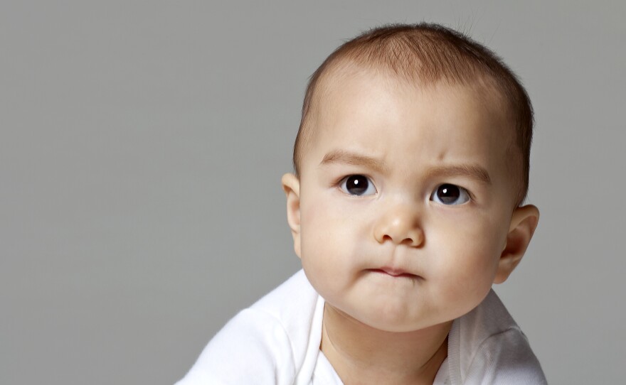  Close-up photo of a baby boy (6-9 months) biting lower lip.