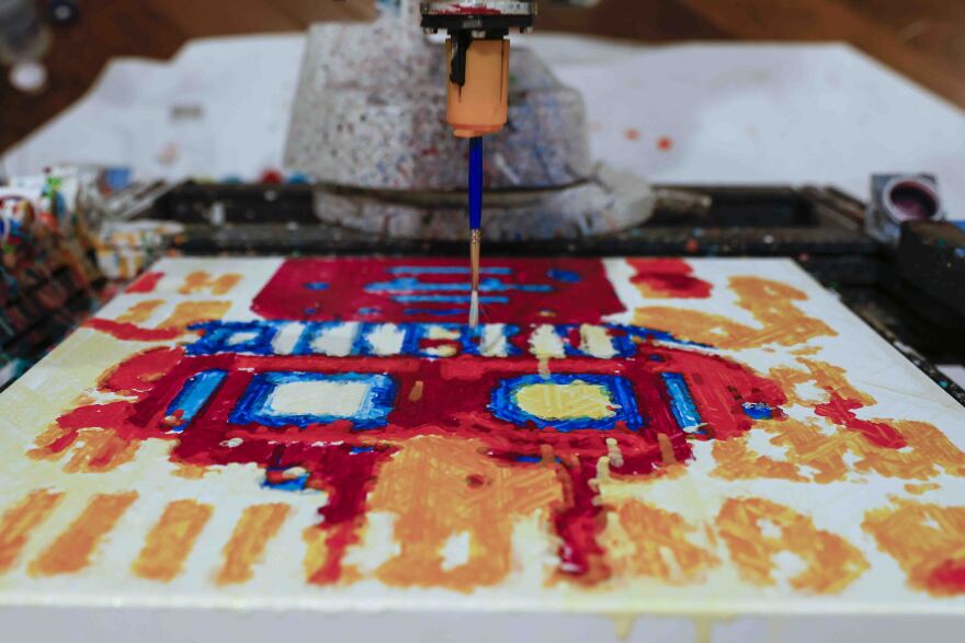 A robot paints a canvas.