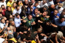 Brazilian Sen. Flavio Bolsonaro wearing a green shirt and looking up in the middle of a crowd