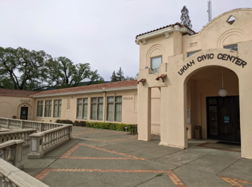 A pinkish building with a courtyard and a sign above an arched doorway, reading, "Ukiah Civic Center."