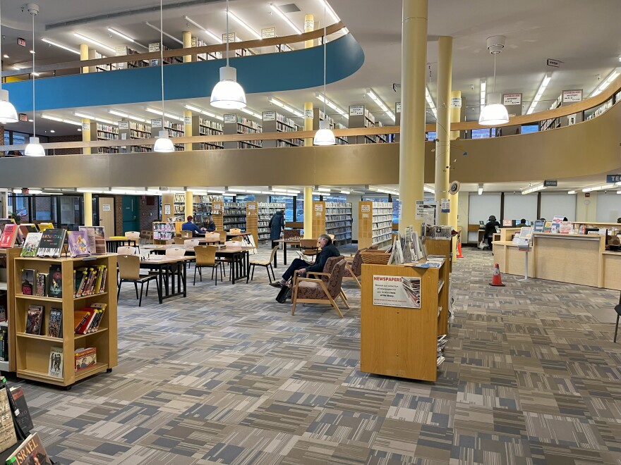 Tables, chairs and books inside a large room at the Fletcher Free Library.