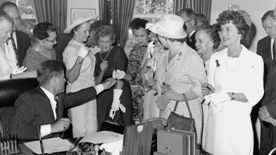 President Kennedy passes out pens on June 10, 1963, after signing the Equal Pay Act.