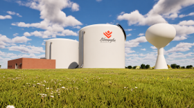 A brick building with two large white water silos and a water tower
