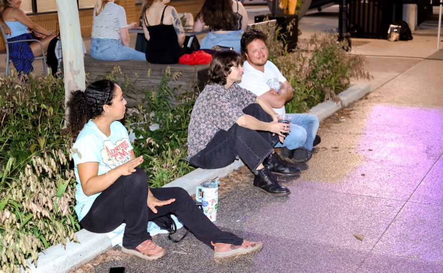 Audience members enjoying local music on a summer evening.