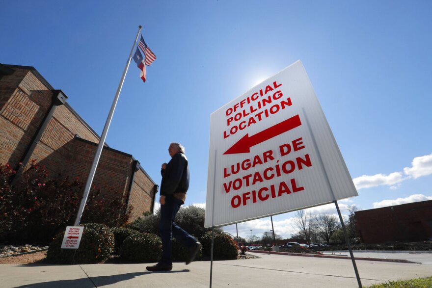 In this Feb. 26, 2020 file photo, using both the English and Spanish language, a sign points potential voters to an official polling location during early voting in Dallas.