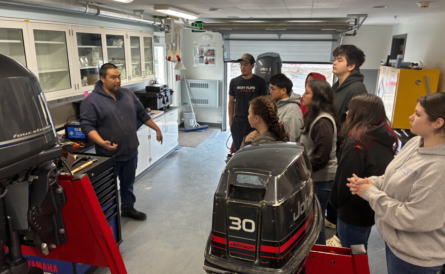 Introduction to Outboard Systems students stand in UAF's Bristol Bay Campus Applied Science Building workshop as instructor Wassilie Tilden teaches.
