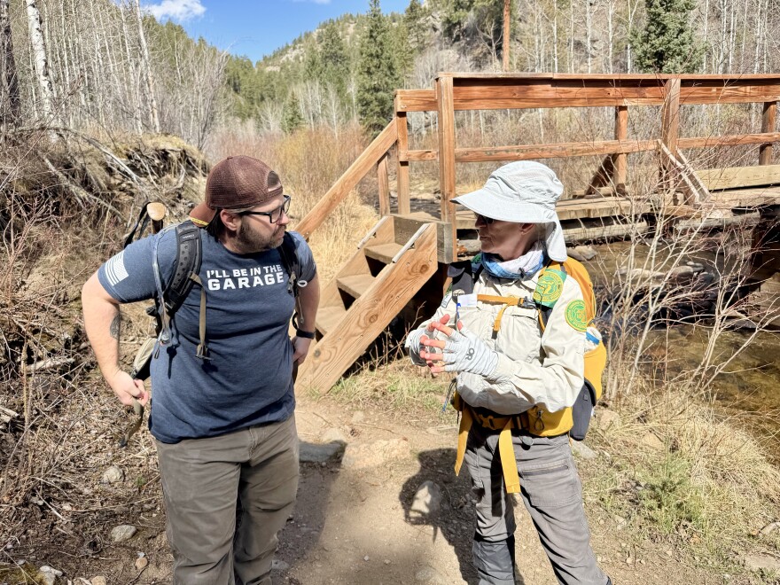 A volunteer forest ranger talks with a hiker on a trail
