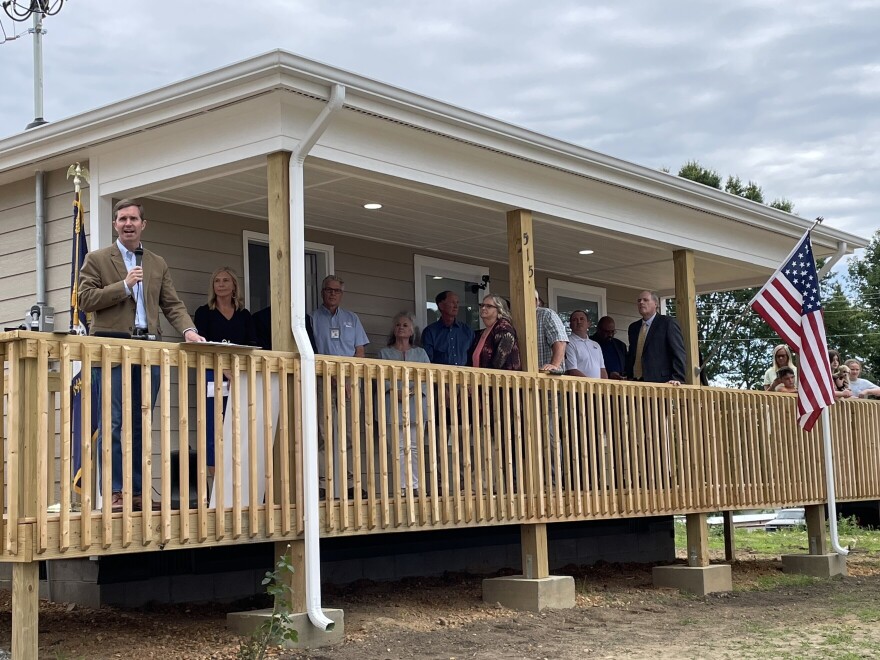 Gov. Andy Beshear and other state and local officials speak on the front porch of Billy and Barbara Patterson's new home.