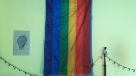 The rainbow flag and transgender flag hang on George's son's wall.