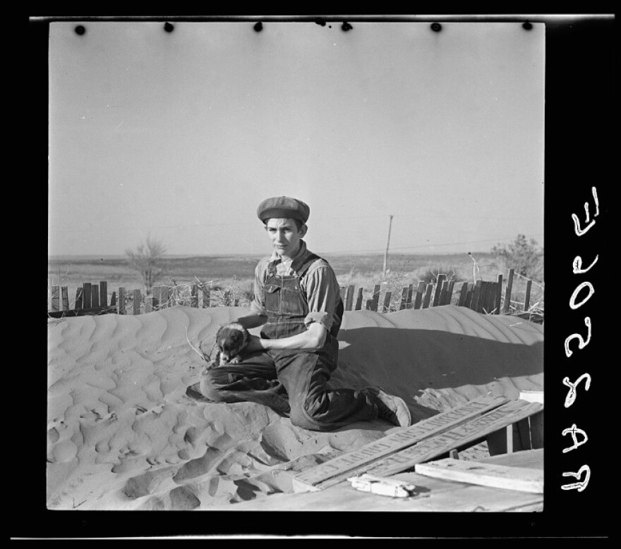 This photo from the Dust Bowl in 1936 shows a farmer's son playing on one of the large soil drifts that threaten to cover up his home near Liberal, Kansas. (Photo courtesy of the Farm Security Administration/Library Of Congress)