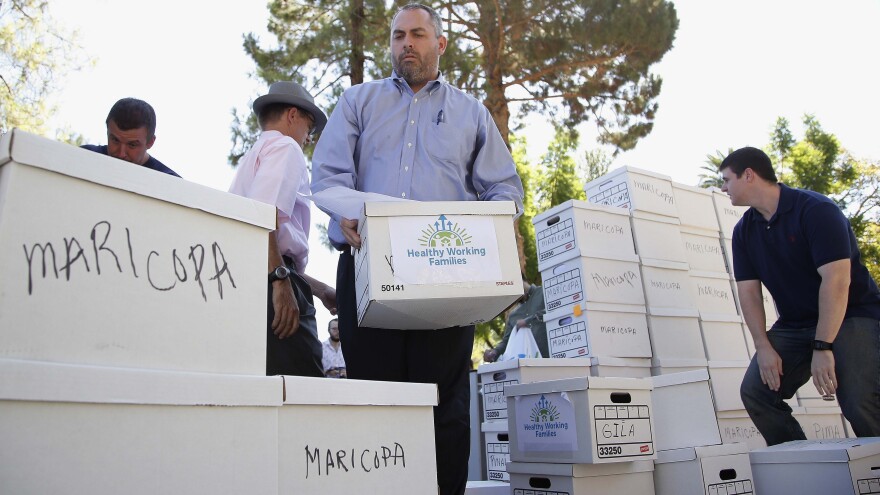 State Elections Director Eric Spencer helps arrange petitions being delivered to the Capitol by advocates of raising Arizona's minimum wage on July 7, 2016, in Phoenix.
