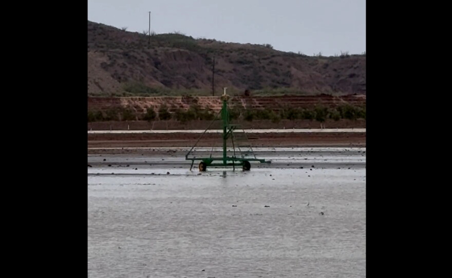 Photo of water coming over the top of the dam in the distance