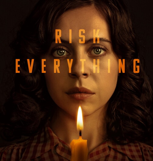 A woman holds a single candle below her face. Above the candle is text, which reads "Risk Everything."