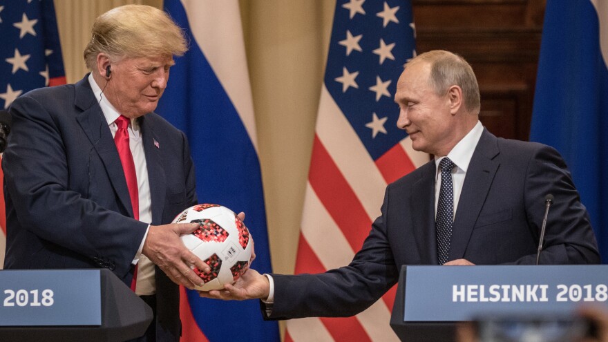 Russian President Vladimir Putin hands President Trump a World Cup soccer ball during a joint news conference after their summit on Monday in Helsinki.