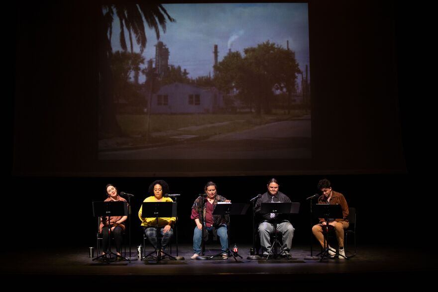 Five people sit on stage. An image of a house is projected behind them. 