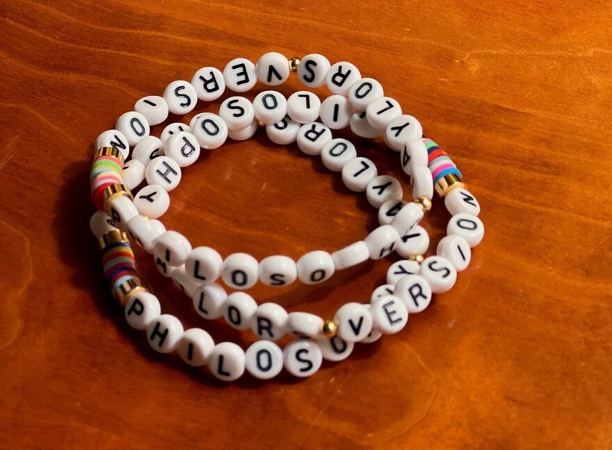 Three intertwined friendship bracelets, with letters spelling out words including Taylor and philosophy.