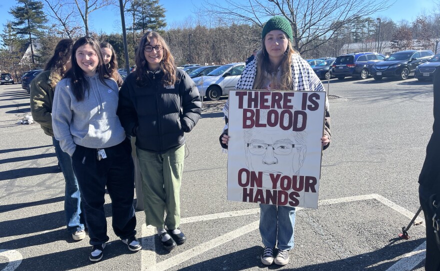 UMass Amherst students holding signs protesting the university's involvement with defense contractor, Raytheon, outside the Eastern Hampshire District Court in Belchertown.