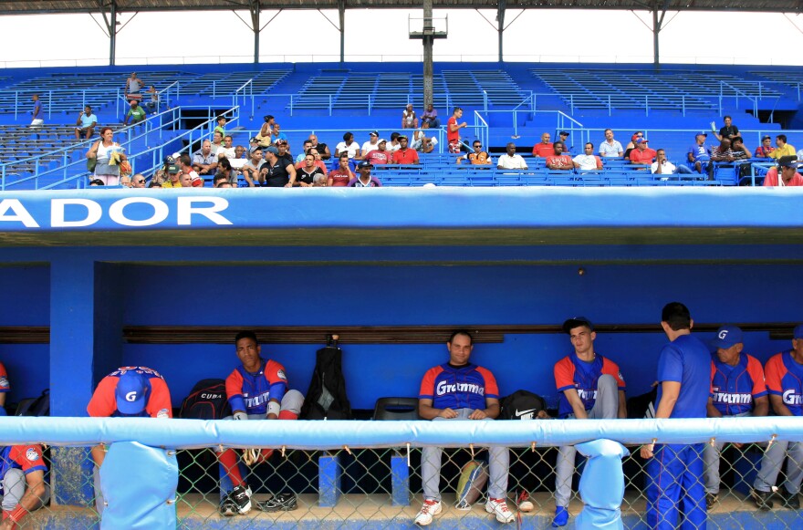 Players for the Alazanes de Granma sit in the dugout at Latin American Stadium.