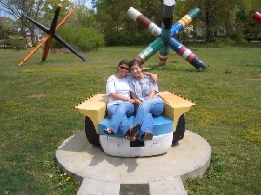 APR's Kristen Taylor, right, and a friend sit in Gordon Chandler's artwork, which he says was inspired by a local resident known as \"Billy Bicycle\"