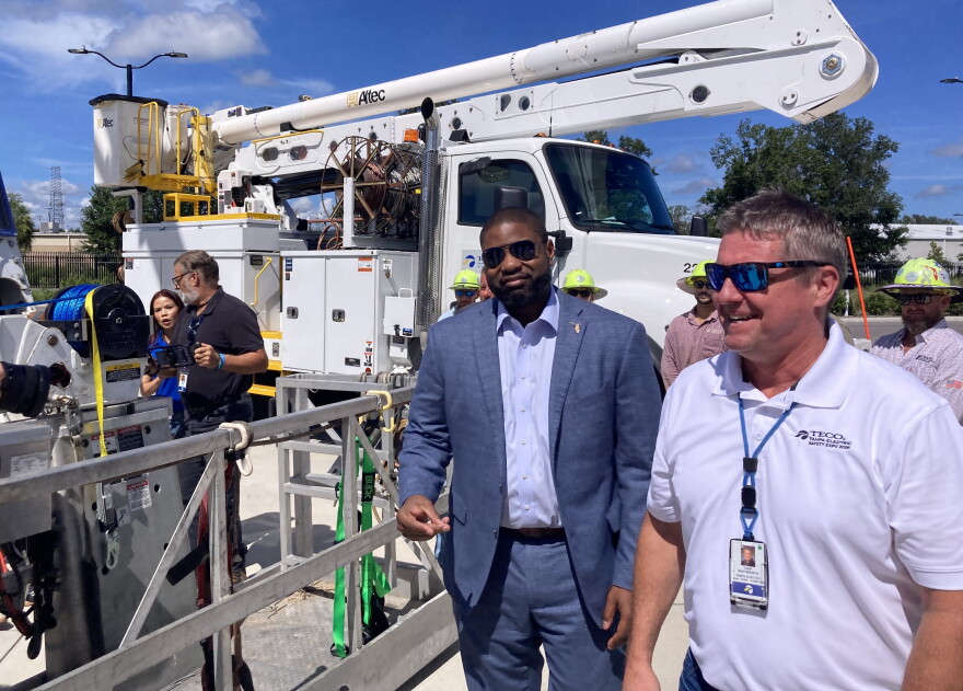 Two men standing outside next to a bucket truck