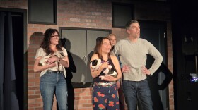 People on a stage hold puppies.
