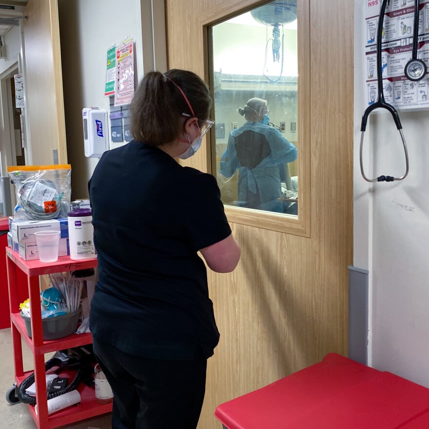 A health care worker peers into a patient's room while a medical team attends to a patient in the COVID-19 ward at Harborview Medical Center in Seattle on January 14, 2022.