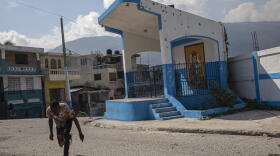  Near a bullet-pocked Catholic shrine, a Haitian man keeps low to avoid gunshots as he runs across a gang-controlled street in Port-au-Prince this month.