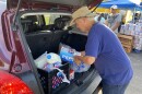 Volunteers load food in the backs of vehicles at a food distribution event at Wings of Faith Fellowship Church near Ocala.