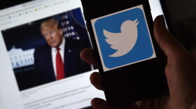 In this photo illustration, a Twitter logo is displayed on a mobile phone with a President Trump's picture shown in the background in Arlington, Virginia.