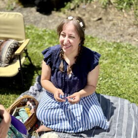Women sitting on a blanket surrounded by sewing projects