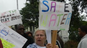 Protestor holding up a sign that says "Safe Water" at a Flint Water Crisis protest