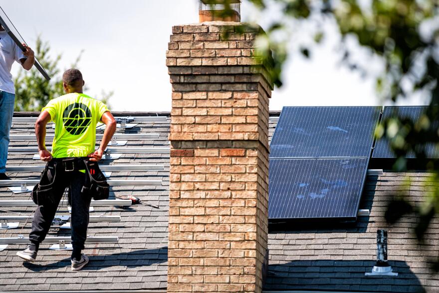 A worker installs rooftop solar panels on a home in Northern Virginia. (Image via Shutterstock)