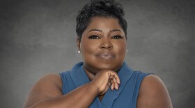 A woman poses against a gray studio backdrop.