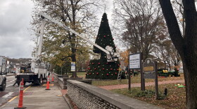 City workers use a bucket truck to assemble a tree on the Old Capitol lawn.