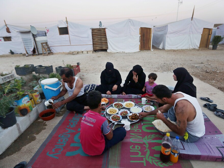 Syrian refugees break their fast outside their tent at a Syrian refugee camp in Marj, Lebanon, on June 29. The World Food Program says it has suspended a food voucher program serving more than 1.7 million Syrian refugees because of a funding crisis.