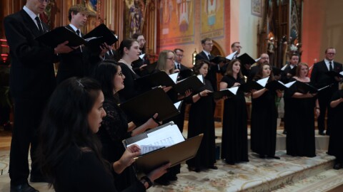 choir of men and women dressed in black and standing in a semi-circle in a church