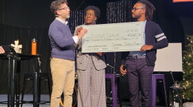 Sycamore Creek pastor Tom Arthur hands an oversized check to Justice League of Greater Lansing founder Willye Bryan and president Prince Solace during a service on Dec. 10, 2023.