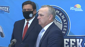 Florida education commissioner Richard Corcoran talks to reporters at a press conference at Boggy Creek Elementary in Kissimmee on Monday November 30th, as Gov. Ron DeSantis looks on. Image: Florida Channel. 
