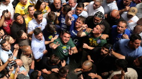 Brazilian Sen. Flavio Bolsonaro wearing a green shirt and looking up in the middle of a crowd