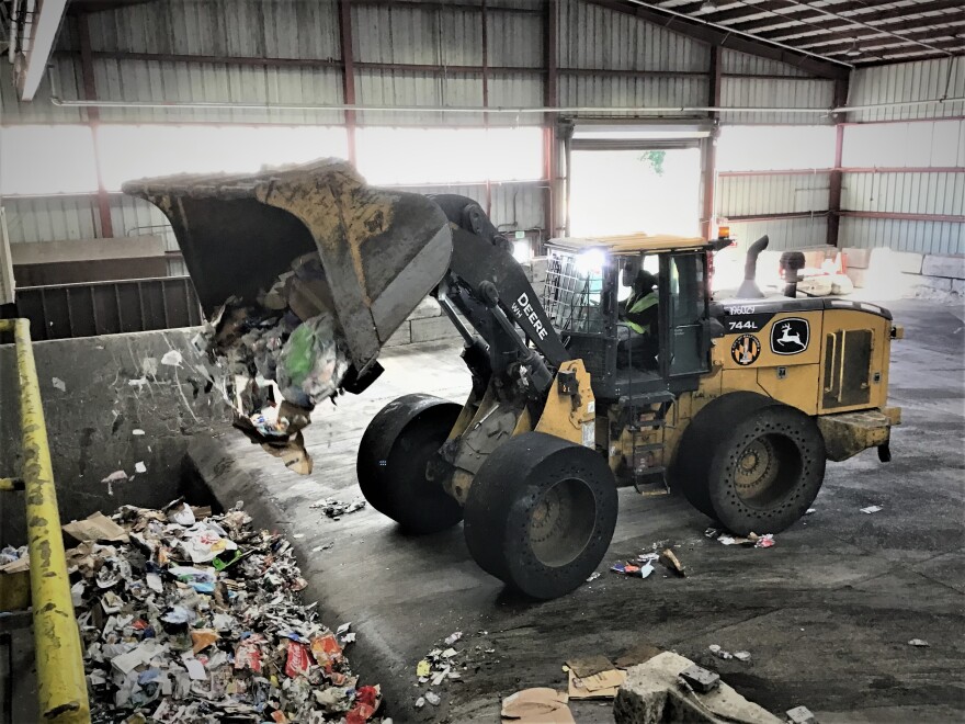 A front-end loader shovels recyclables into a compacting pit at Northwest Transfer Station (photo credit: Aaron Henkin / WYPR)