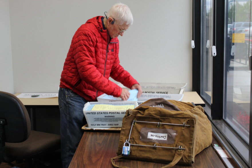 An employee at the Linn County Clerk’s Office puts ballots he collected from dropboxes at a local courthouse into trays, pairing a yellow auditing form to track how many ballots there are in each tray.