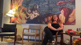 Christine Wilson, executive director of Women Writing for (a) Change sits underneath a painting donated by a former student of the program.