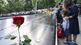 Mourners pause at the north reflecting pool as flowers are placed in the names of the dead at the National September 11 Memorial and Museum, Friday, Sept. 11, 2020, in New York. (AP Photo/John Minchillo)