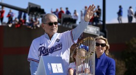 Riding with the Commissioner's Trophy, Texas Rangers manager Bruce Bochy, left, waves to fans as his wife Kim Seib, right, looks on during a parade for the baseball World Series-champion team in Arlington.