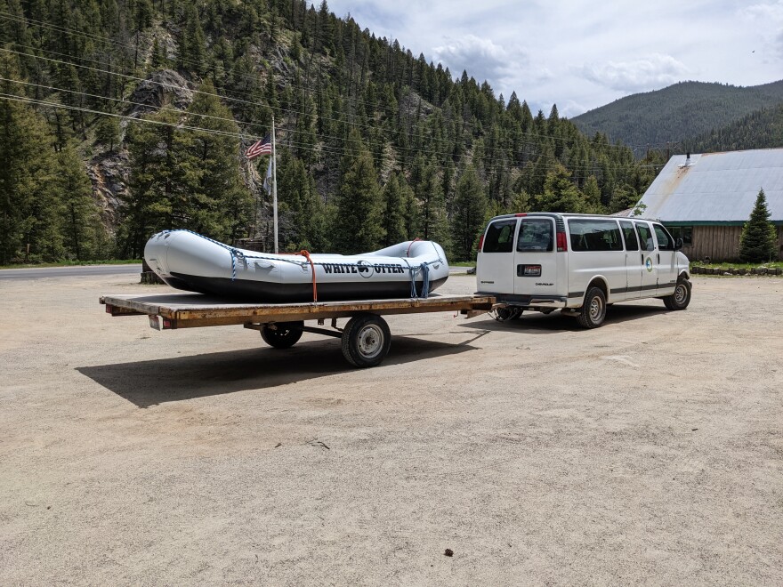 A white van pulls a trailer with a rafting boat on top