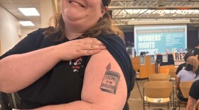 Ann Dorn, who serves on the steering committee of Tacoma for All, poses at an event informing people about the workers' bill of rights with the tattoo she got after the group's initiative for a tenant bill of rights passed in 2023.