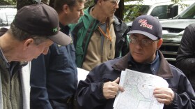 A man in a cap shows a map to another man in a cap.