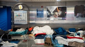 People sleeping among blankets, clothes, shoes and bags lie on a hard floor near O'Hare.